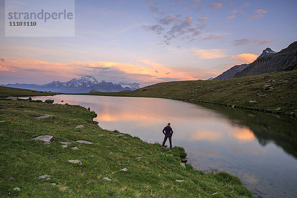 Wanderer am Ufer bewundert die rosa Farben der Morgendämmerung  die sich im Campagneda-See spiegeln  Malenco-Tal  Valtellina  Lombardei  Italien  Europa