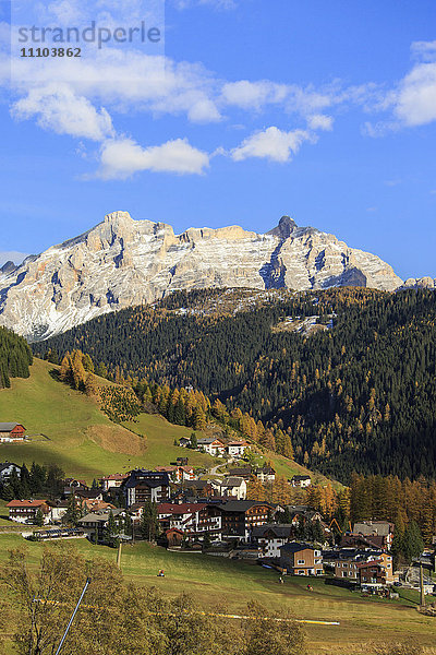 Bunte Wälder umrahmen das Dorf und die hohen Gipfel im Herbst  Grödnertal  Südtirol  Trentino-Südtirol  Italien  Europa