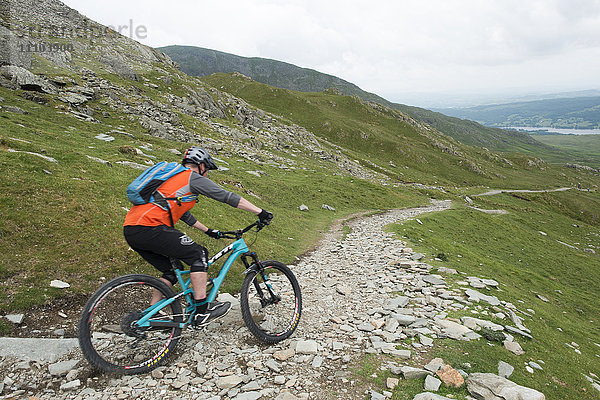 Ein Mountainbiker fährt den Weg vom Old Man of Coniston im Lake District National Park hinunter  Cumbria  England  Vereinigtes Königreich  Europa