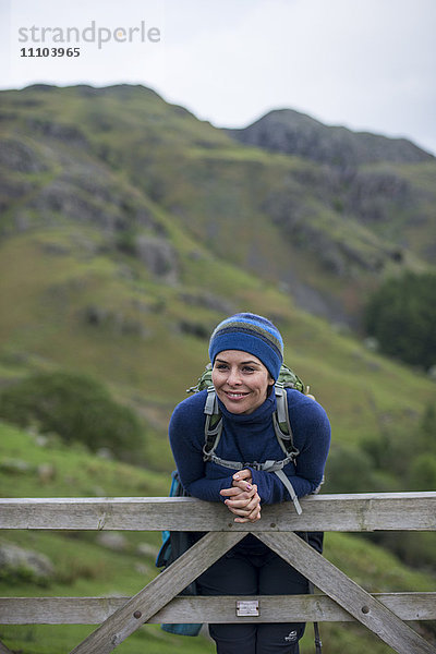 Eine Frau ruht sich auf einem Tor im Great Langdale Tal im Lake District  Cumbria  England  Vereinigtes Königreich  Europa