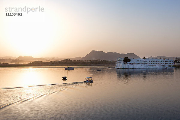 Boot auf dem Weg zum Lake Palace Hotel in der Abenddämmerung. Das Hotel befindet sich in der Mitte des Pichola-Sees in Udaipur  Rajasthan  Indien  Asien