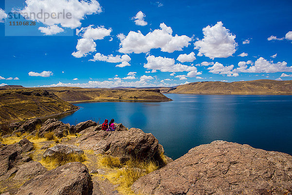 Zwei Menschen sitzen am Rande des Titicacasees  Peru  Südamerika