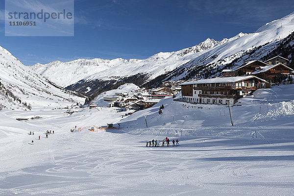 Gruppen von Skifahrern genießen die winterlichen Bedingungen mit dem Dorf Obergurgl und den dahinter liegenden Otztaler Alpen  Tirol  Österreich  Europa