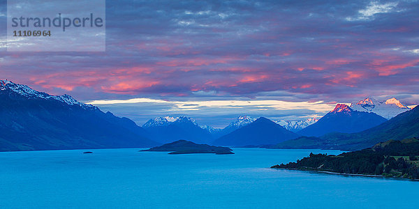 Der Mount Earnslaw und die benachbarten Berggipfel in den Südalpen werden von den letzten Sonnenstrahlen hinter dem Lake Wakatipu beleuchtet  Otago  Südinsel  Neuseeland  Pazifik