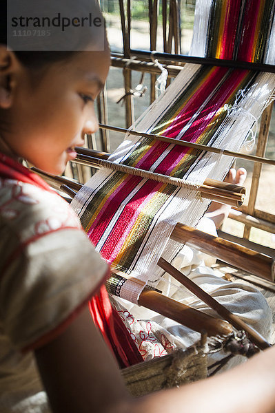 Ein kleines Mädchen erlernt die Kunst des Webens auf einem Handwebstuhl  Chittangong Hill Tracts Region  Bangladesch  Asien