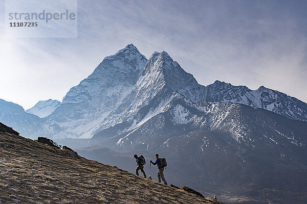 Wanderer besteigen einen kleinen Gipfel oberhalb von Dingboche in der Everest-Region  um den Sonnenaufgang mit der Ama Dablam in der Ferne zu erleben  Himalaya  Nepal  Asien