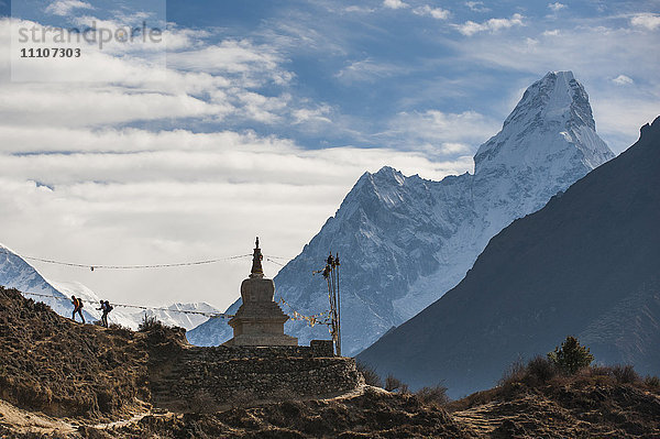 Wanderer in der Nähe eines Chorten in der Everest-Region mit dem Gipfel der Ama Dablam in der Ferne  Himalaya  Nepal  Asien