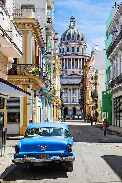Ein Oldtimer geparkt auf der Straße neben kolonialen Gebäuden mit dem ehemaligen Parlamentsgebäude im Hintergrund  Havanna  Kuba  Westindien  Karibik  Mittelamerika