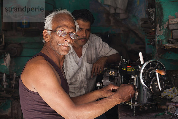 Mann repariert eine alte Nähmaschine in der Stadt Jodhpur  Rajasthan  Indien  Asien