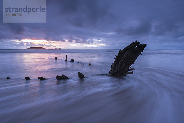 Schiffswrack der Helvetia am Strand von Rhossili  Blick in Richtung Worms Head bei Sonnenuntergang  Rhossili  Gower  Wales  Vereinigtes Königreich  Europa
