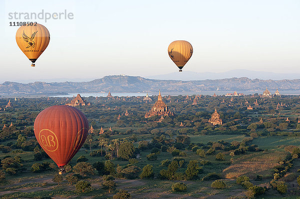 Heißluftballons fliegen über die Terrakotta-Tempel von Bagan mit dem Irrawaddy-Fluss in der Ferne  Bagan (Pagan)  Mandalay Division  Myanmar (Burma)  Asien