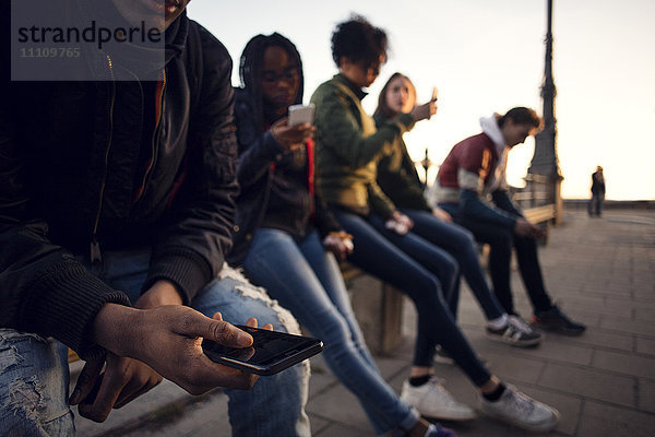 Freunde beim Telefonieren auf dem Geländer am Stadtplatz