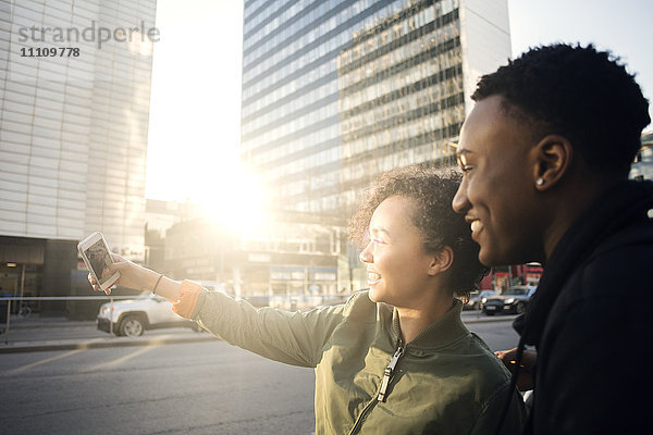 Teenager nimmt Selfie mit Freund durch Smartphone durch die Stadt Straße