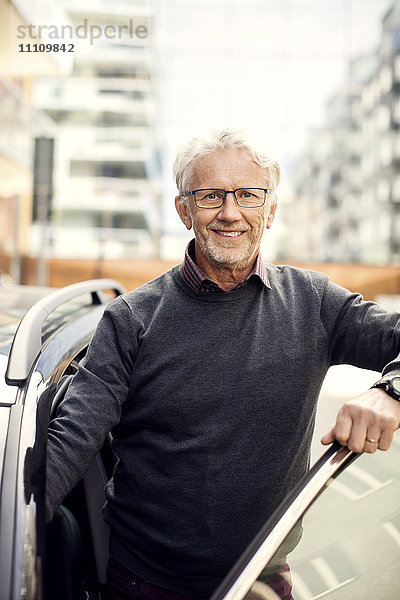 Porträt eines lächelnden älteren Mannes beim Aussteigen aus dem Auto in der Stadt