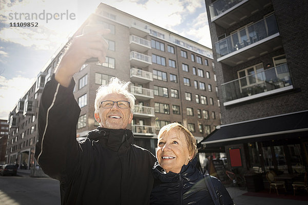 Senior Paar nimmt Selfie durch Smartphone  während er in der Stadt steht.