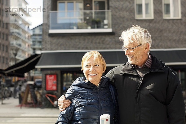 Lächelndes Seniorenpaar steht gegen das Gebäude