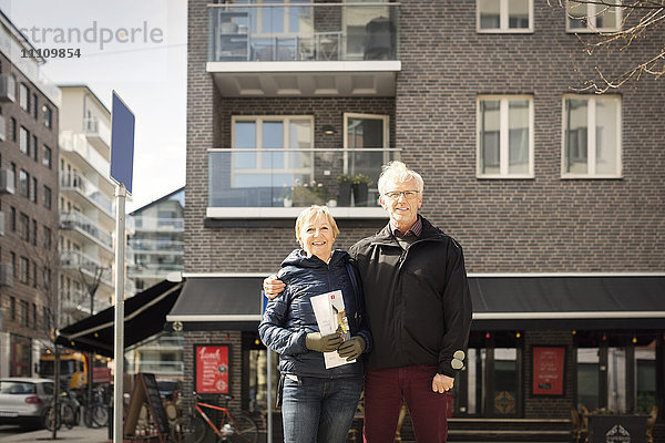 Porträt eines lächelnden älteren Paares  das sich gegen das Gebäude stellt