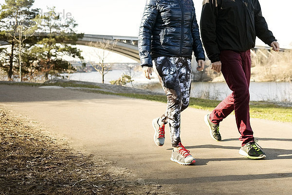 Niedriger Abschnitt von Mann und Frau in Sportbekleidung beim Gehen auf der Straße