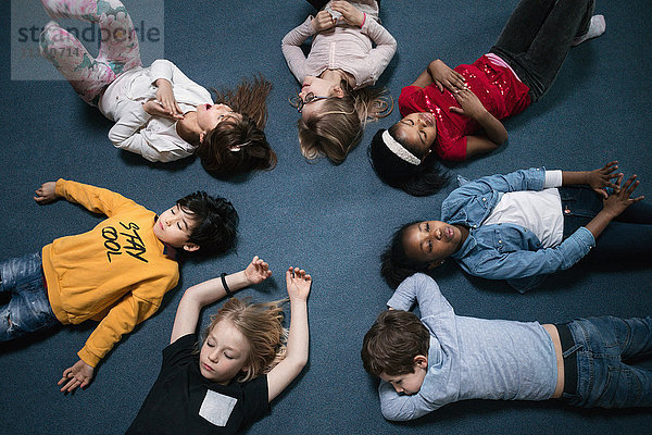 Direkt über der Aufnahme von Schulkindern  die im Klassenzimmer auf dem Boden liegen.