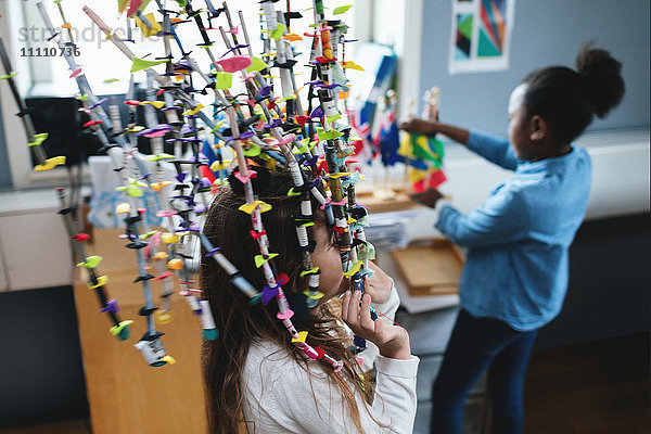 Mädchen spielt mit der Dekoration  während ein Freund die Fahnen im Klassenzimmer ansieht