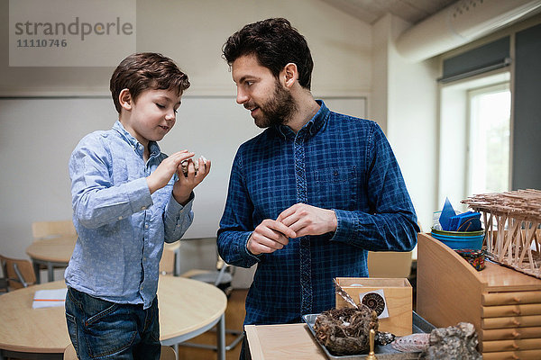 Lehrer assistiert männlichen Schülern bei der Erstellung von Projekten in der Schule