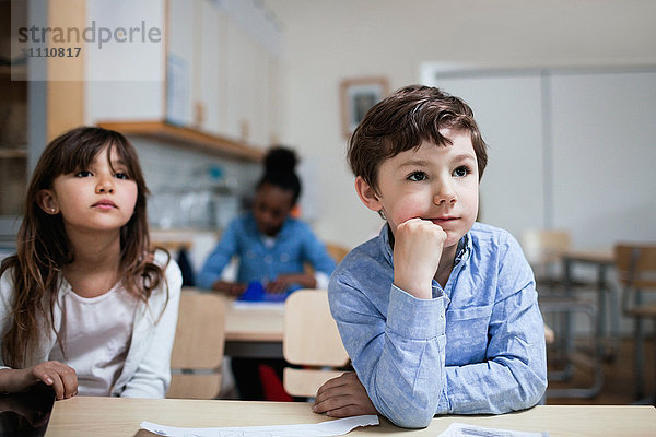 Konzentrierte Kinder sitzen am Schreibtisch im Klassenzimmer