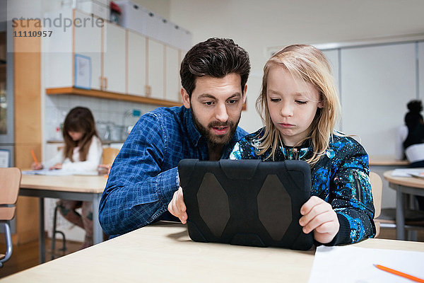 Männlicher Lehrer erklärt den Schülern den Umgang mit dem digitalen Tablett im Unterricht.