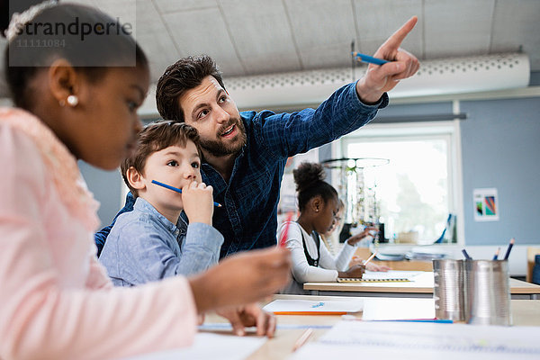 Lehrer diskutiert mit dem Jungen  während er in der Schule auf ihn zeigt.