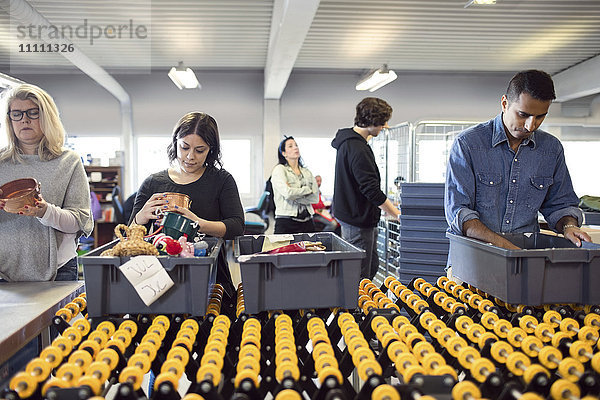 Freiwillige  die in der Werkstatt nach Objekten in der Kiste suchen.