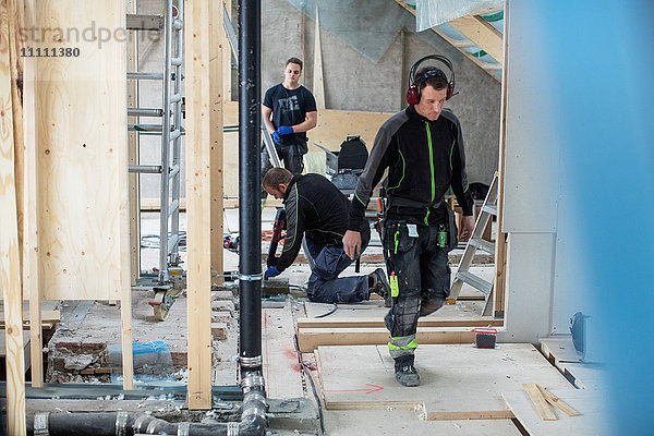 Handwerker  die auf der Baustelle auf unordentlichem Boden arbeiten