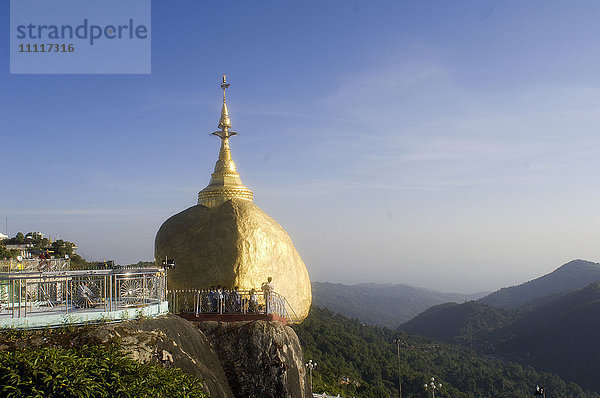 Asien  Myanmar  Kyaiktiyo ist ein Ort der ersten Pilgerfahrt zur buddhistischen Religion. Es wird angenommen  dass die sieben Buddha-Hüte  die sich in der obersten Stupa befinden  im perfekten Gleichgewicht zueinander stehen. Der Felsblock ist buchstäblich mit Gold überzogen  da die Pilger Blattgold auf dem Felsen zerrieben haben. Sonnenaufgang