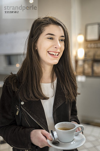 Lächelnde Frau mit einer Tasse Kaffee in der Hand