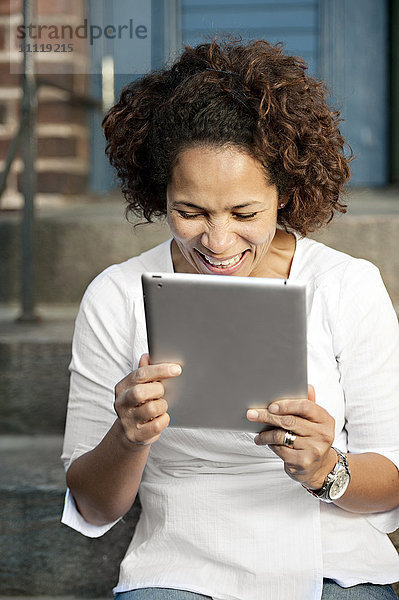 Frau hält digitales Tablet  lachend