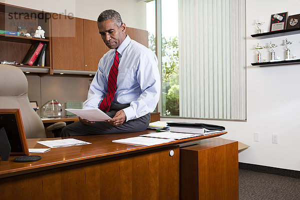 Afroamerikanischer Geschäftsmann sitzt am Schreibtisch