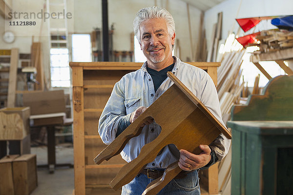 Hispanischer Handwerker lächelnd im Atelier