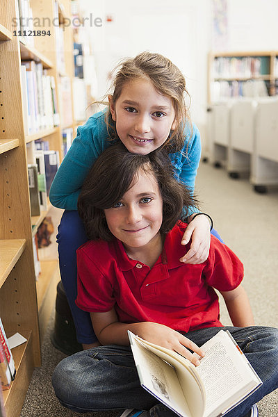 Lächelnde kaukasische Studenten in der Bibliothek