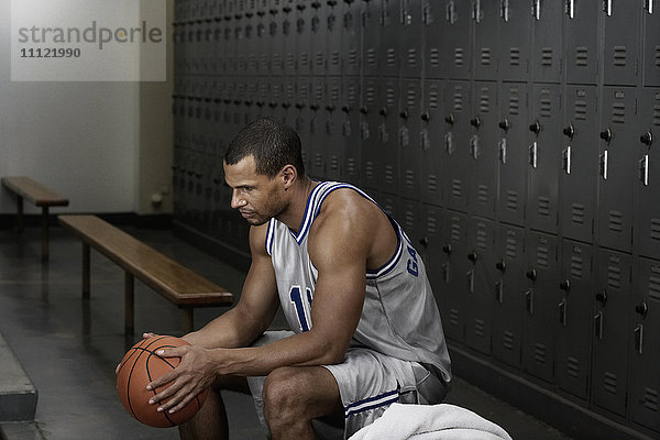 Gemischtrassiger Basketballspieler sitzt in der Umkleidekabine