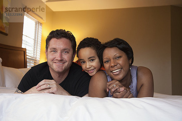 Lächelnde Familie auf dem Bett liegend
