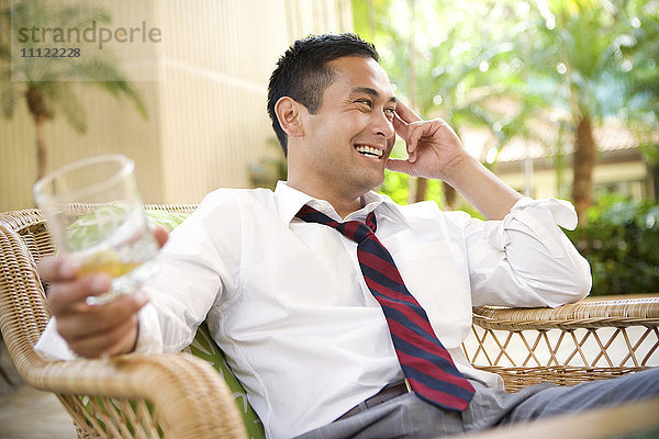 Lächelnder Mann gemischter Rasse trinkt auf Terrasse