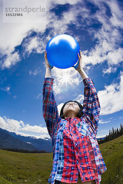 Asiatischer Mann hebt Ball in abgelegenem Feld