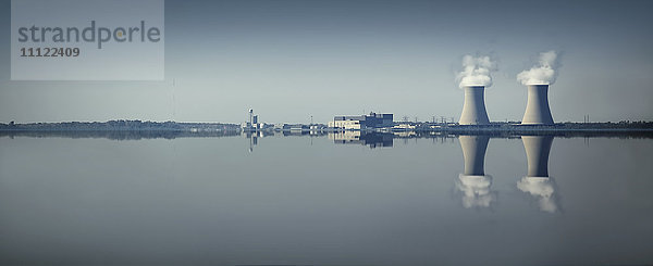 Schornsteine und Fabrik spiegeln sich im stillen See