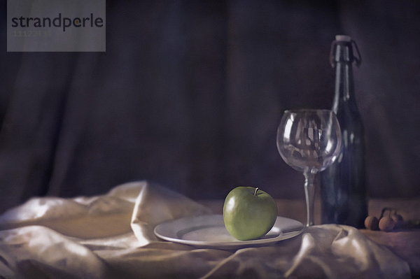 Apfel  Weinglas und Flasche auf Tischtuch