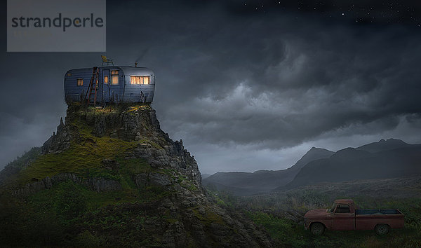 Beleuchteter Wohnwagen auf felsigem Berggipfel
