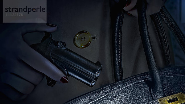 Frau steckt Pistole in Handtasche