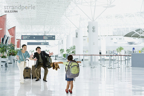 Asiatische Großeltern begrüßen ihre Enkelin am Flughafen