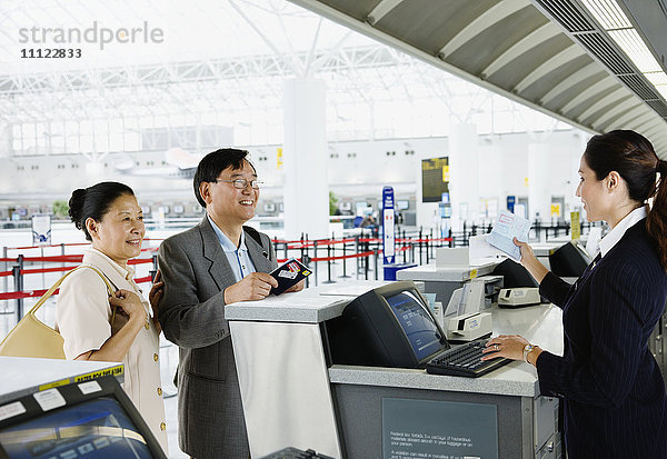 Asiatisches Paar beim Einchecken am Flughafen