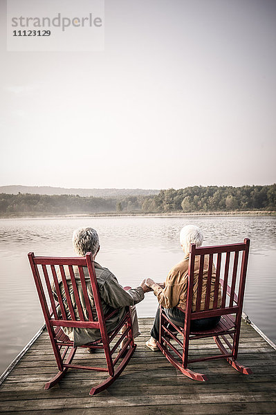 Älteres kaukasisches Paar sitzt auf einem Holzsteg
