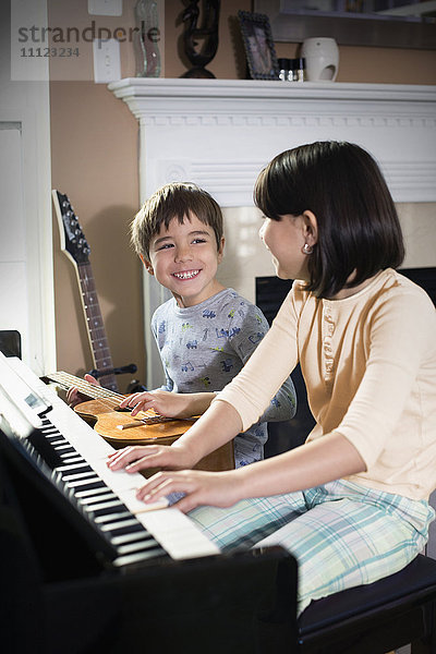 Hispanische Kinder spielen Musik im Wohnzimmer