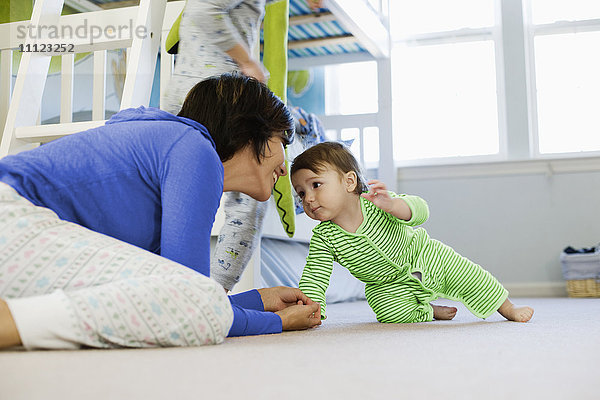 Hispanische Mutter mit Kleinkind im Schlafzimmer