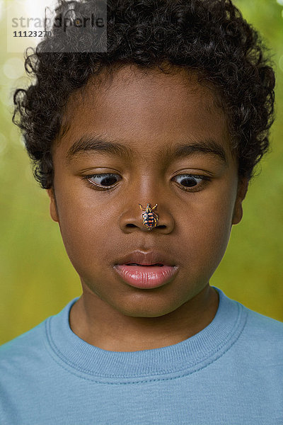 Afrikanischer Junge mit Insekt auf der Nase